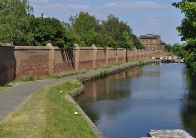 Hanwell Locks, hospital wall, former lunatic asylum a large imposing brick wall beside the canal as it stretches ahead